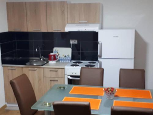 uma cozinha com uma mesa, um fogão e um frigorífico em Apartmani Tajra em Visoko