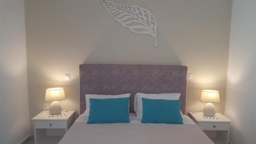 a bedroom with a bed with blue pillows and two lamps at Maria Studios in Paleokastritsa