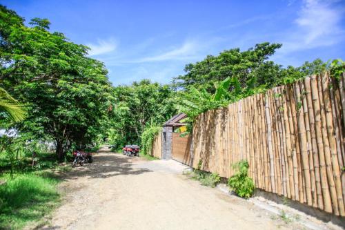 a wooden fence next to a dirt road with trees at Lua Villas in Santa Teresa Beach