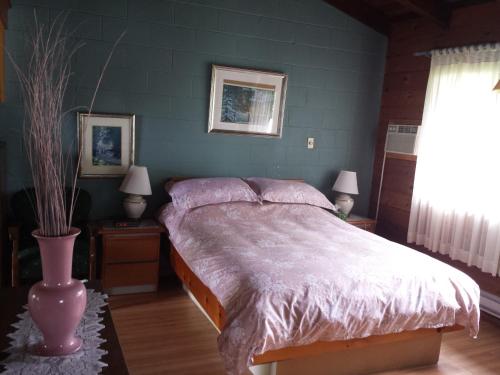 a bedroom with a bed with a pink comforter at Motel Le Charentais in Sorel