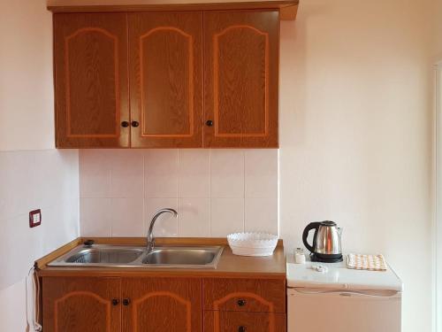 a kitchen with wooden cabinets and a sink at Apartments Rudi in Orikum