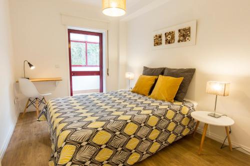 Un dormitorio con una cama con almohadas amarillas y una mesa. en Casa Oliveira in Downtown Porto II, en Oporto