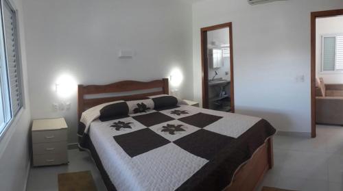 a bedroom with a bed with a black and white quilt at Pousada e Camping Lagoa da Conceição in Florianópolis