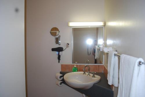 a bathroom with a sink and a mirror and towels at Rainforest Motel in Mission Beach