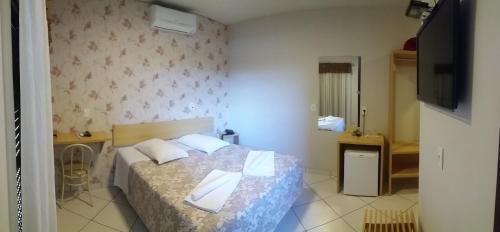 a bedroom with a bed with two pillows and a television at Hotel Da Vila in Joinville