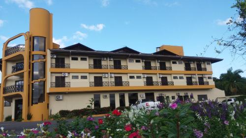 a large yellow building with flowers in front of it at Hotel Da Vila in Joinville