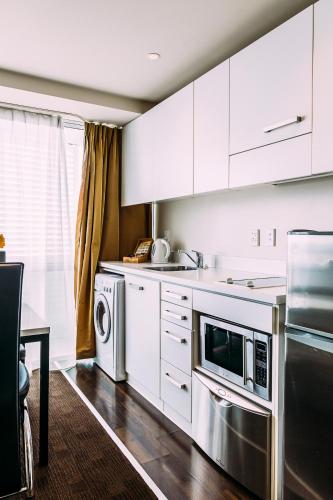 a kitchen with white cabinets and a stainless steel appliance at The Quadrant Hotel & Suites in Auckland