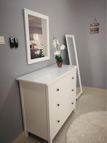 a white dresser with a mirror and flowers on it at Arianna Homestay in Pasir Gudang