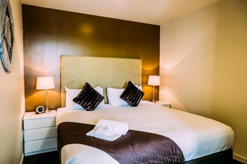 a bedroom with a large white bed with two lamps at The Quadrant Hotel & Suites in Auckland