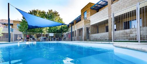 a blue umbrella is hanging over a swimming pool at Quest Wagga Wagga in Wagga Wagga