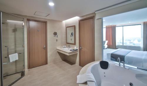 a bathroom with a bed and a sink and a tub at Muong Thanh Luxury Ca Mau Hotel in Cà Mau