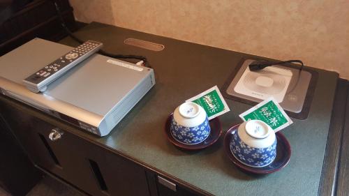 a table with three cups and a laptop on it at Hotel Sango (Adult only) in Muroran