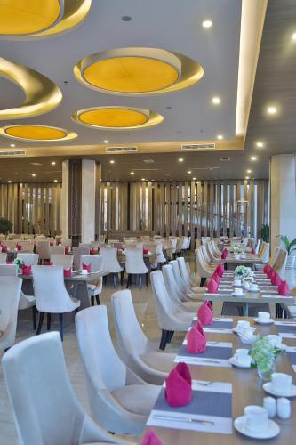 a dining room with tables and white chairs at Muong Thanh Luxury Ca Mau Hotel in Cà Mau