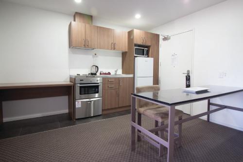 a small kitchen with a table and a refrigerator at Nesuto St Martins Apartment Hotel in Auckland
