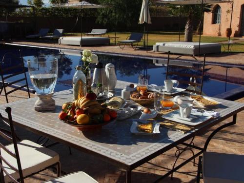 - une table avec de la nourriture à côté de la piscine dans l'établissement Palais Lona, à Marrakech
