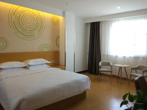 1 dormitorio con 1 cama, mesa y sillas en GreenTree Inn Jinzhong Yuci District North Huitong Road Express Hotel, en Jinzhong