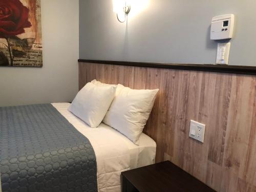 a small bedroom with a bed with white pillows at Petit Hôtel Amara in La Malbaie