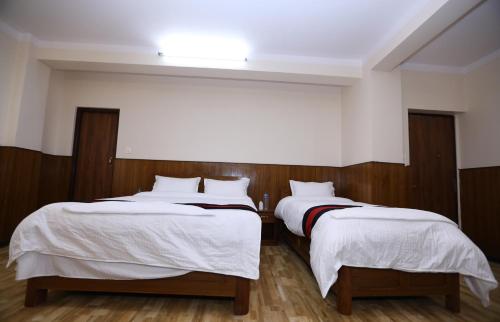 a bedroom with two beds with white sheets at Green Eco Resort in Kirtipur