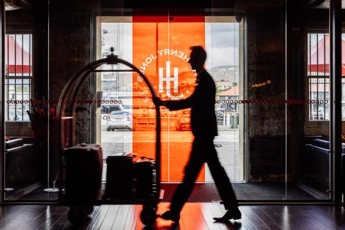 a man standing in front of a building with a suitcase at The Henry Jones Art Hotel in Hobart
