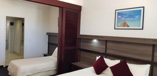 a hotel room with two beds and a mirror at Hotel Le Paris in Noumea