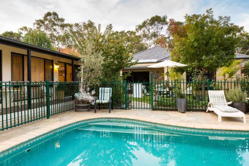 a swimming pool in front of a house with a fence at Courtsidecottage Bed and Breakfast in Euroa