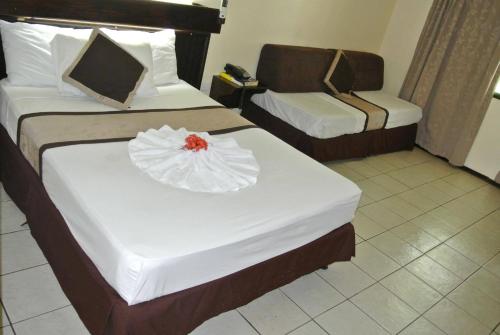 a hotel room with two beds with a flower on it at Grand Eastern Hotel in Labasa
