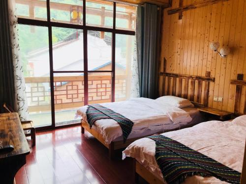 two beds in a room with a large window at Zhangjiajie one step to heaven inn (Yangjiajie ticket office) in Zhangjiajie