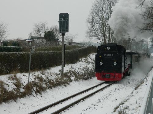 a train traveling down the tracks in the snow at Ferienwohnung "Kranich" im Ferien-Resort Rügen in Sagard