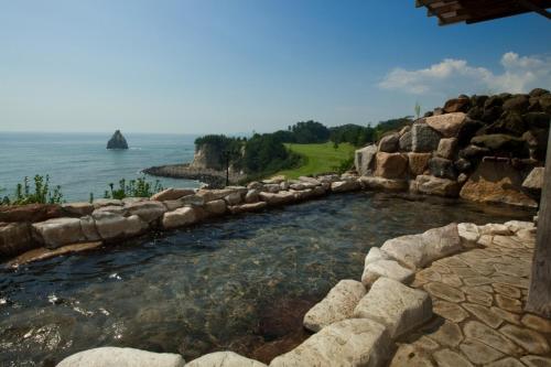 a pool of water with a rock wall next to the ocean at Onahama Ocean Hotel & Golf Club in Iwaki