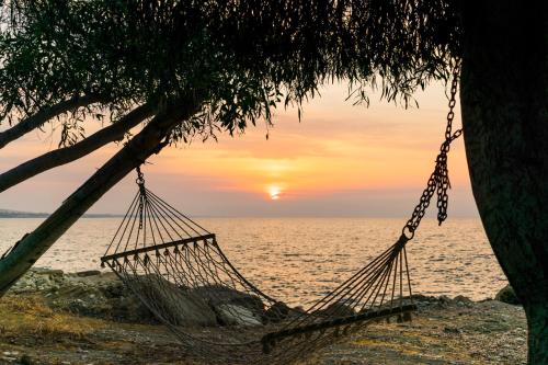 a hammock on the beach with the sunset in the background at Elya Beach Luxury Suites in Ayios Theodhoros