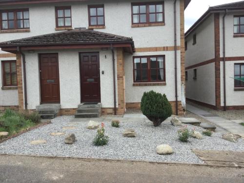 a house with a bunch of rocks in front of it at Culloden Apartment in Inverness