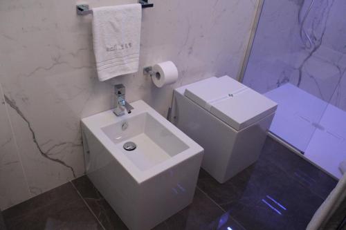 a white bathroom with a toilet and a sink at Kalì B&B in Bari