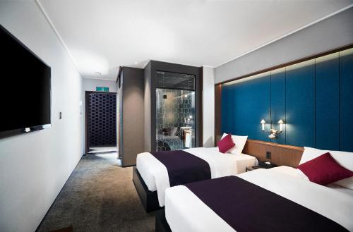 South Vandeco Hotel في بوسان: غرفة فندقية بسريرين وتلفزيون بشاشة مسطحة