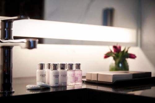 a bathroom counter with four bottles of soap and a lamp at South Vandeco Hotel in Busan