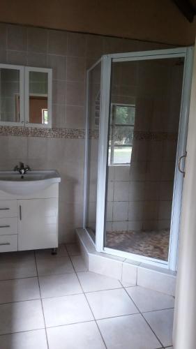a bathroom with a shower and a sink and a mirror at White Mountain Resort in Emhubeni