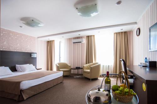 a hotel room with a bed and a table with a bowl of fruit at Sky Hotel Krasnoyarsk in Krasnoyarsk