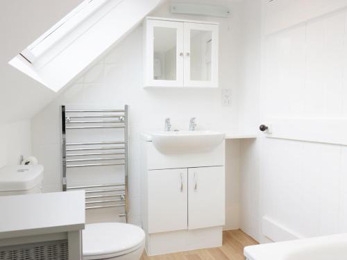La salle de bains blanche est pourvue d'un lavabo et de toilettes. dans l'établissement The Grieves Cottage, à Haddington