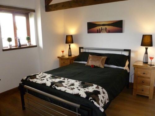 a bedroom with a bed and two lamps and two windows at Buttercup Cottage in Penrith