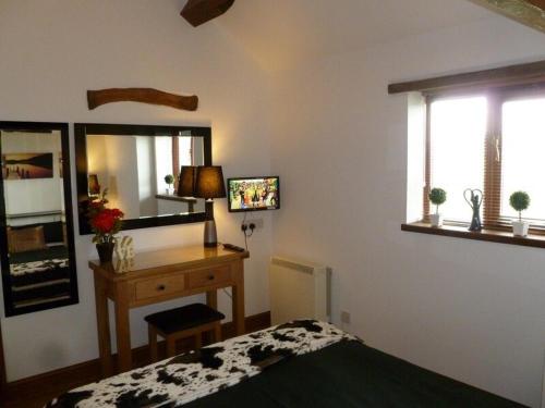 a bedroom with a bed and a desk and window at Buttercup Cottage in Penrith