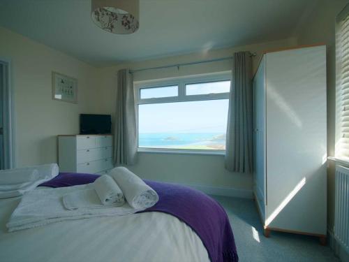 a bedroom with a bed and a large window at Bay View House in Crantock