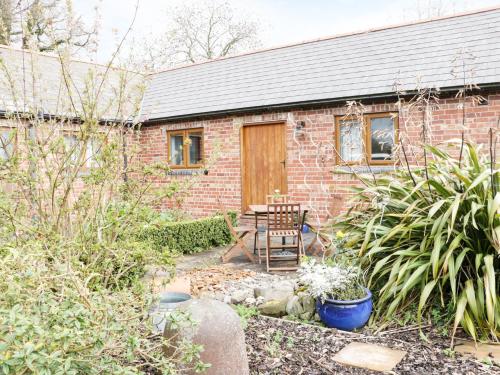 a brick house with a bench in a garden at Acorn Cottage 1 in Petton
