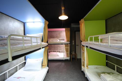 three bunk beds in a room with green walls at Calli Hostel in Busan