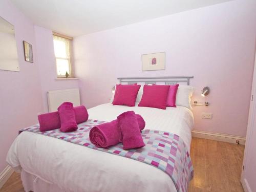 a bedroom with a large bed with pink pillows at Mithian Cottage in St. Agnes