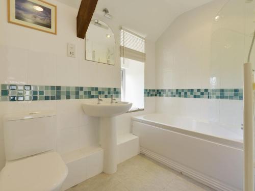 a white bathroom with a sink and a bath tub and a sink at Millers Cottage in Bude