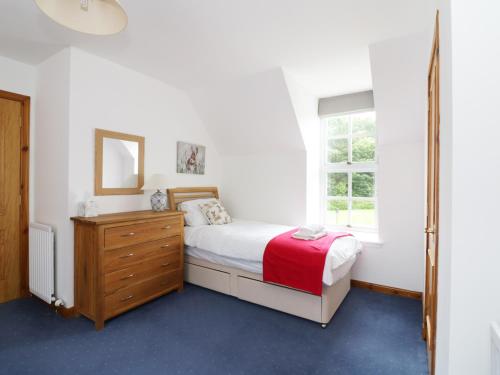 a bedroom with a bed and a dresser and a window at Dunnottar Woods House in Stonehaven
