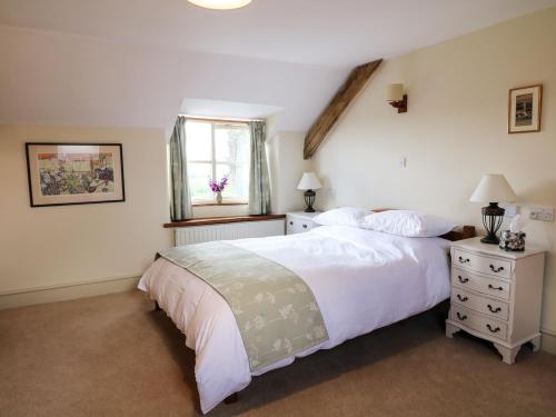 a bedroom with a large white bed and a window at Chilvery Farm Cottage in Okehampton