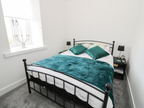 een slaapkamer met een bed met groene lakens en een raam bij Skovhaven in Catton