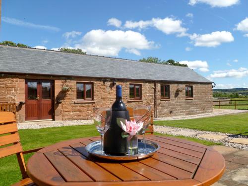a table with a bottle of wine and flowers on it at Daisy Cottage in Penrith