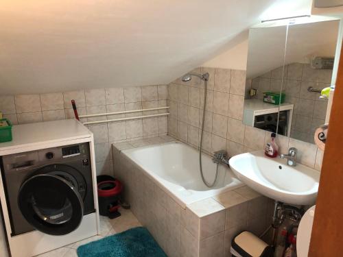 bagno con vasca, lavandino e lavatrice di Apartment Sunset a Portoroz