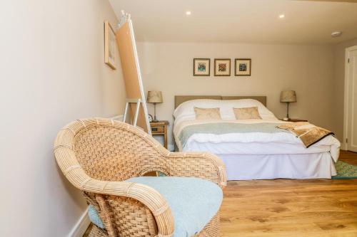 a bedroom with a bed and a wicker chair at Woodpecker Lodge in High Ham